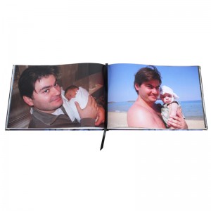 Ein aufgeschlagenes Fotobuch mit zwei Fotos eines Vaters mit seinem Baby