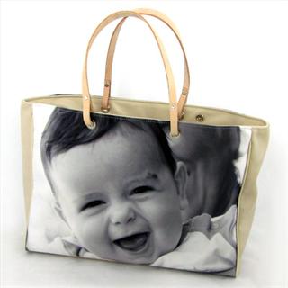 Eine Handtasche aus Leder in beige bedruckt mit einem Foto eines Babys in schwarz/weiss